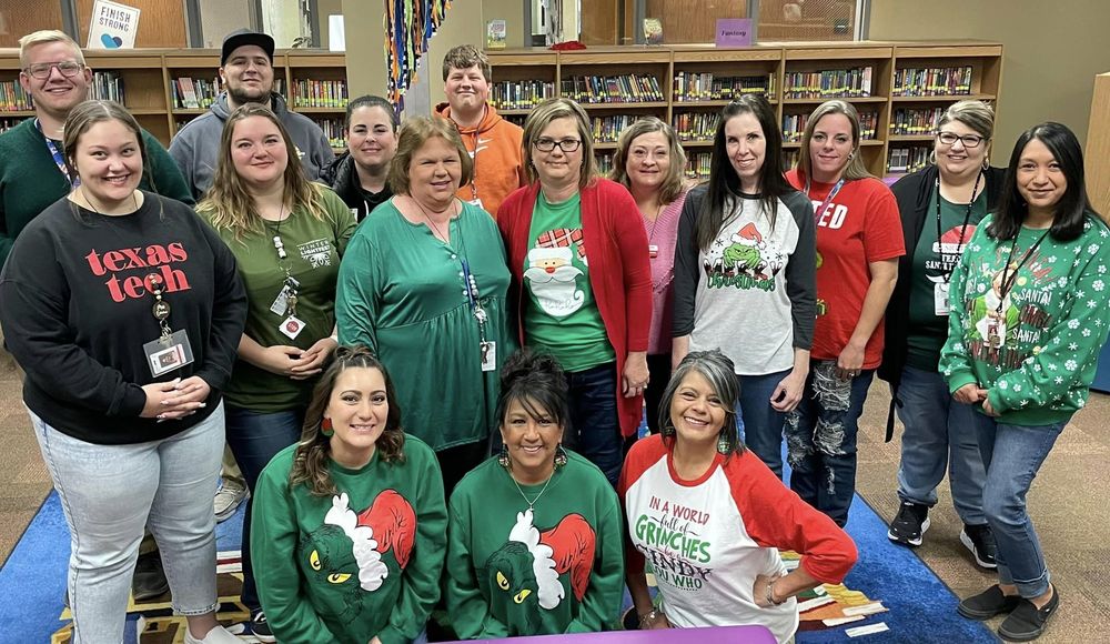 sis staff posing with christmas sweaters all together in the library